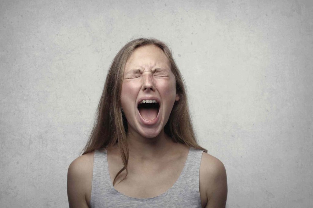 A girl with closed eyes is yelling.