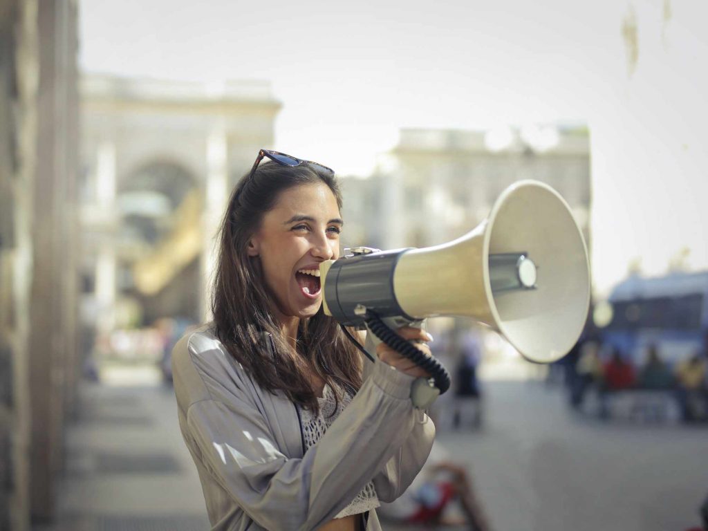 A woman speaks through a loud speaker.